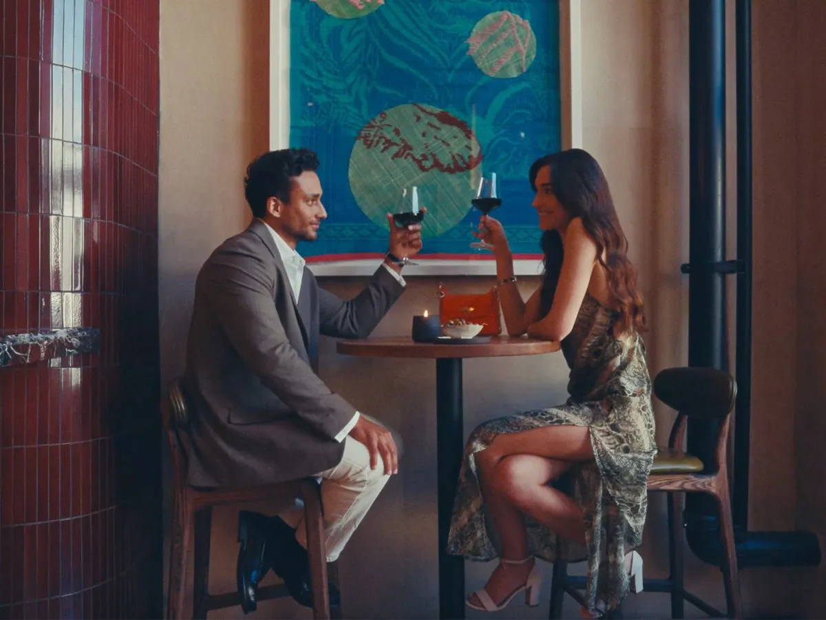 A couple sharing a glass of red wine at a neighbourhood bar
